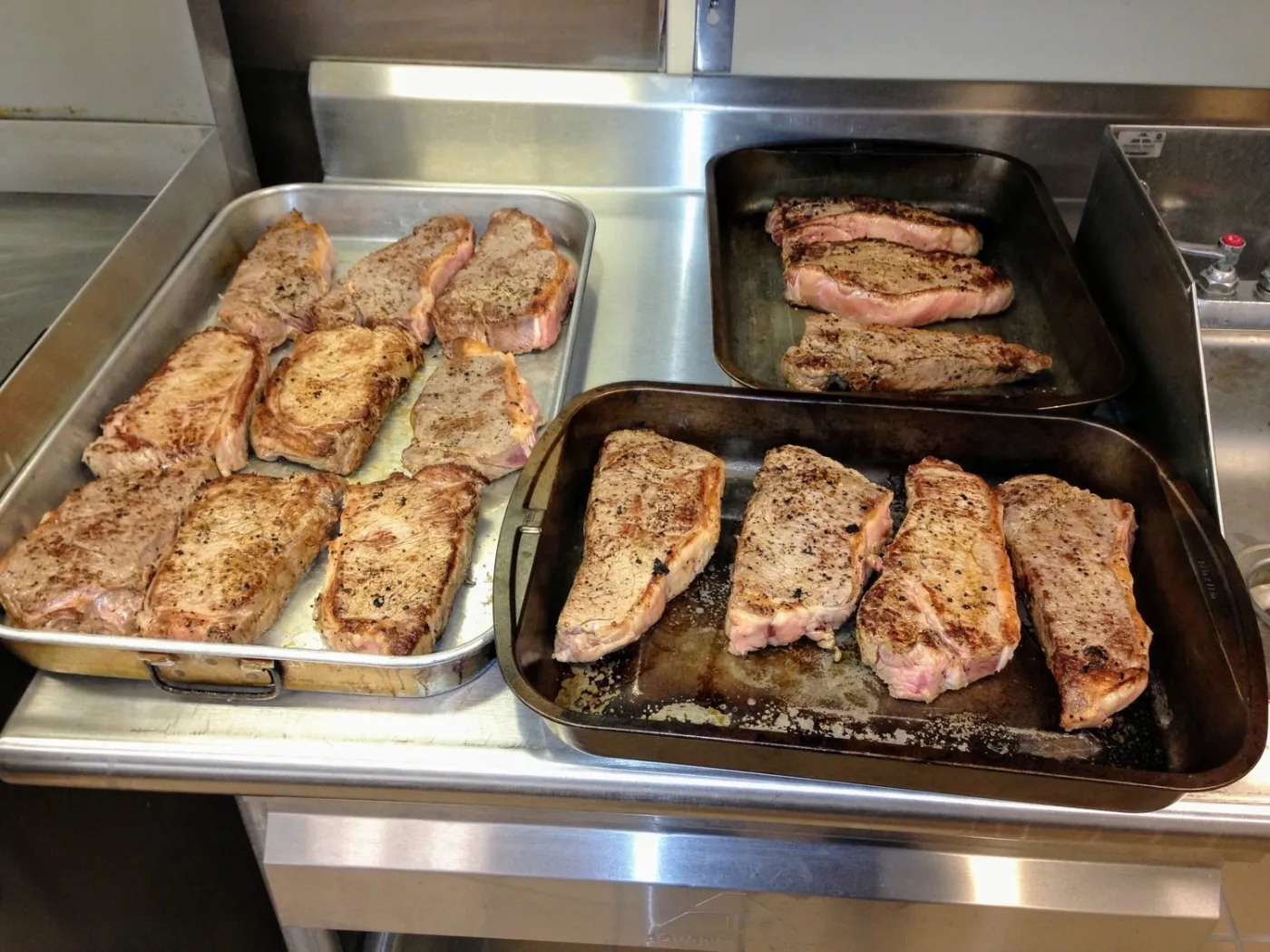 Pans of seared steaks on a firehouse kitchen counter