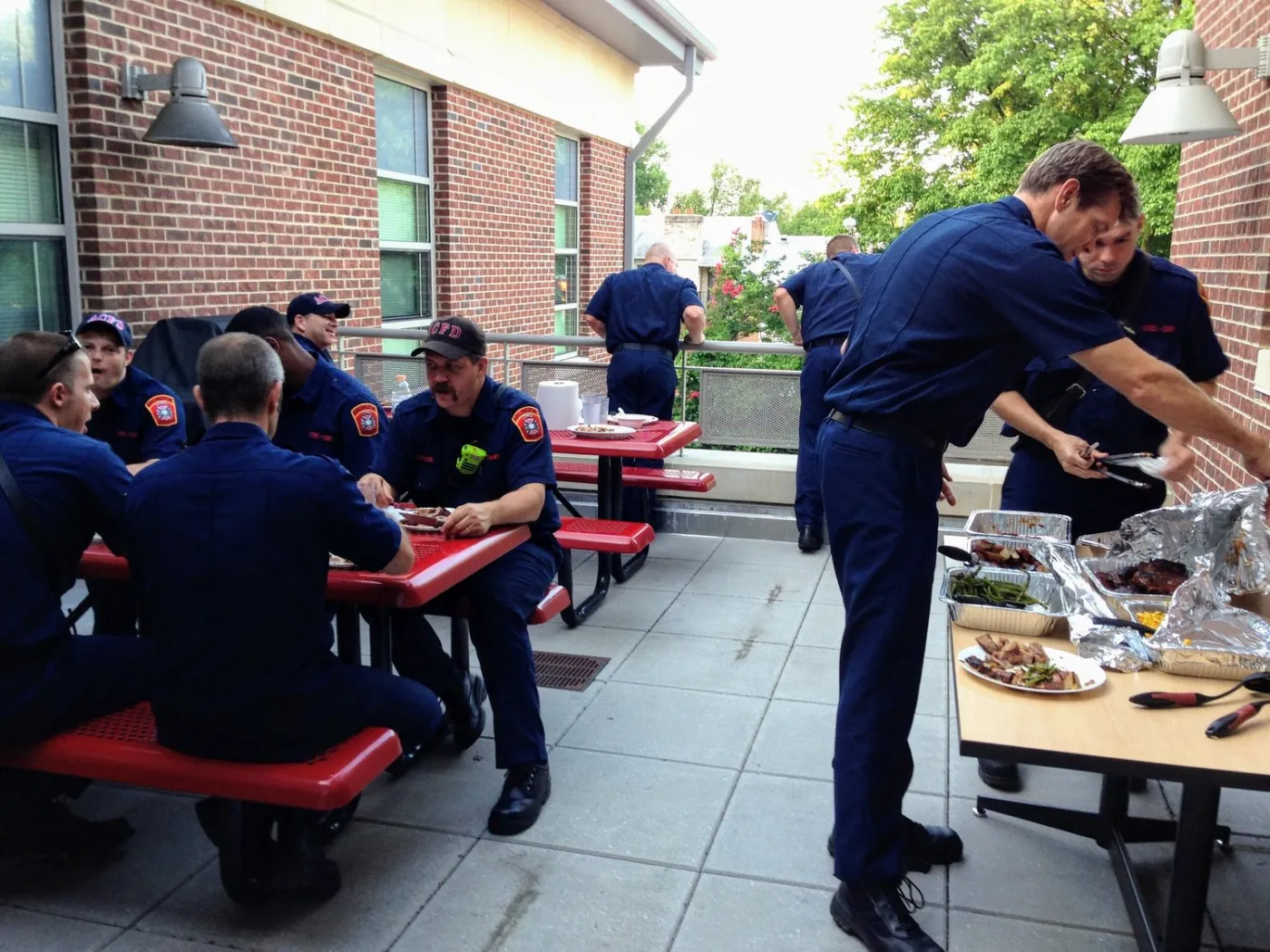 Firefighters eating together at picnic tables outside the station